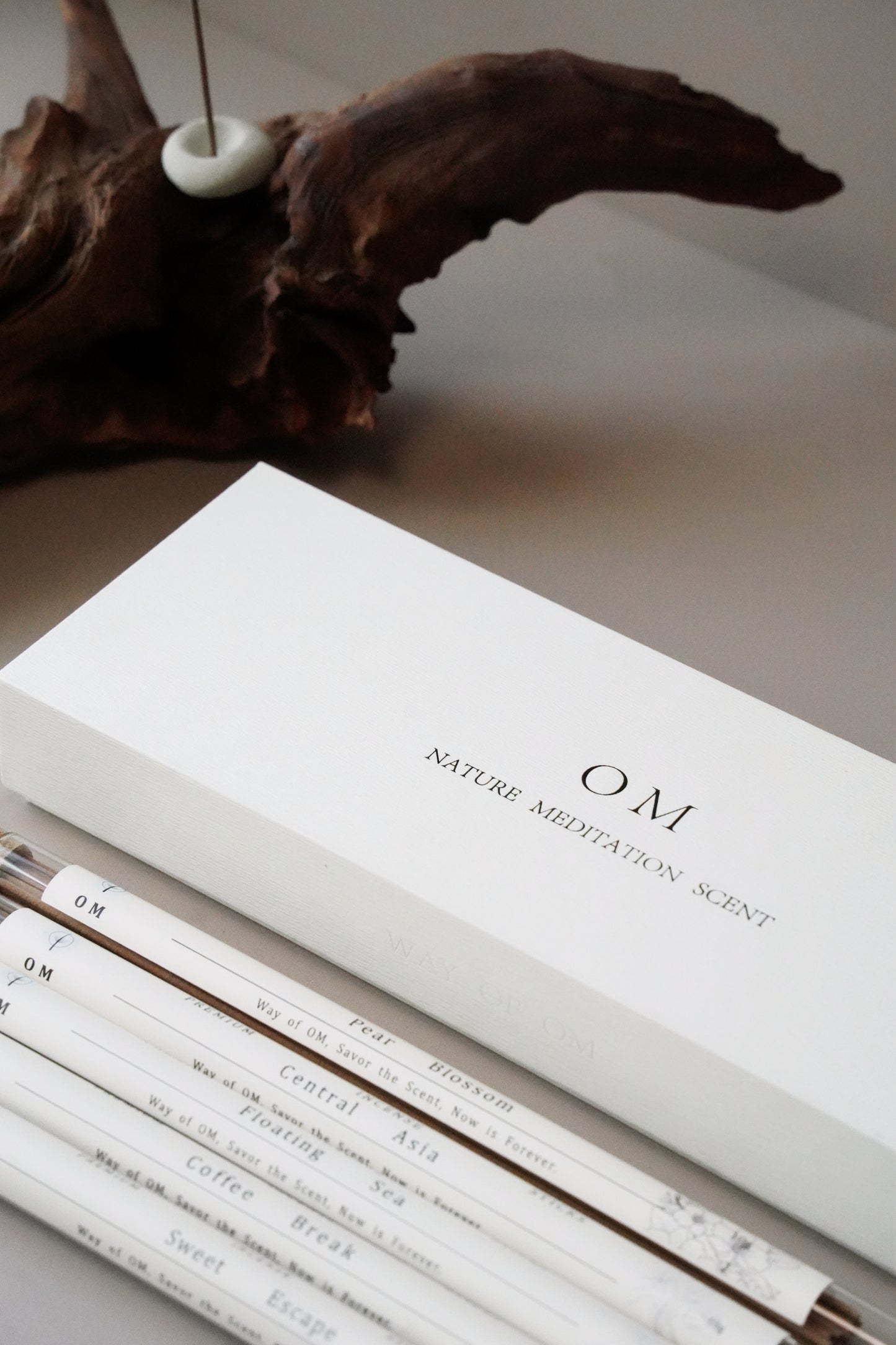 OM 5 DIFFERENT INCENSE PRODUCTS WITH WOODY DECORATION ON THE WHITE TABLE