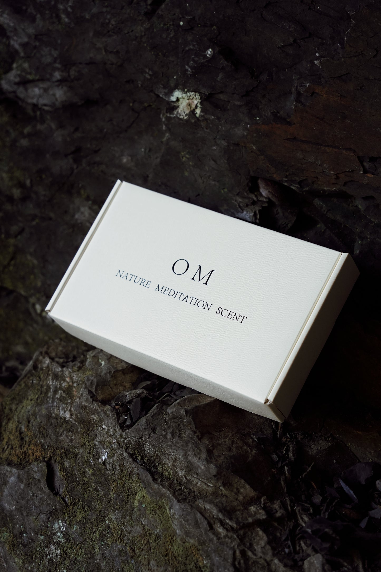 OM incense packaging with white holder, minimal branding against dark natural backdrop