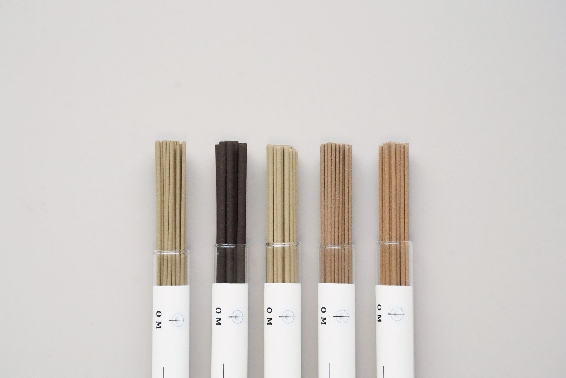 OM incense sticks in elegant tubes arranged on white background – ambergris and floral blend