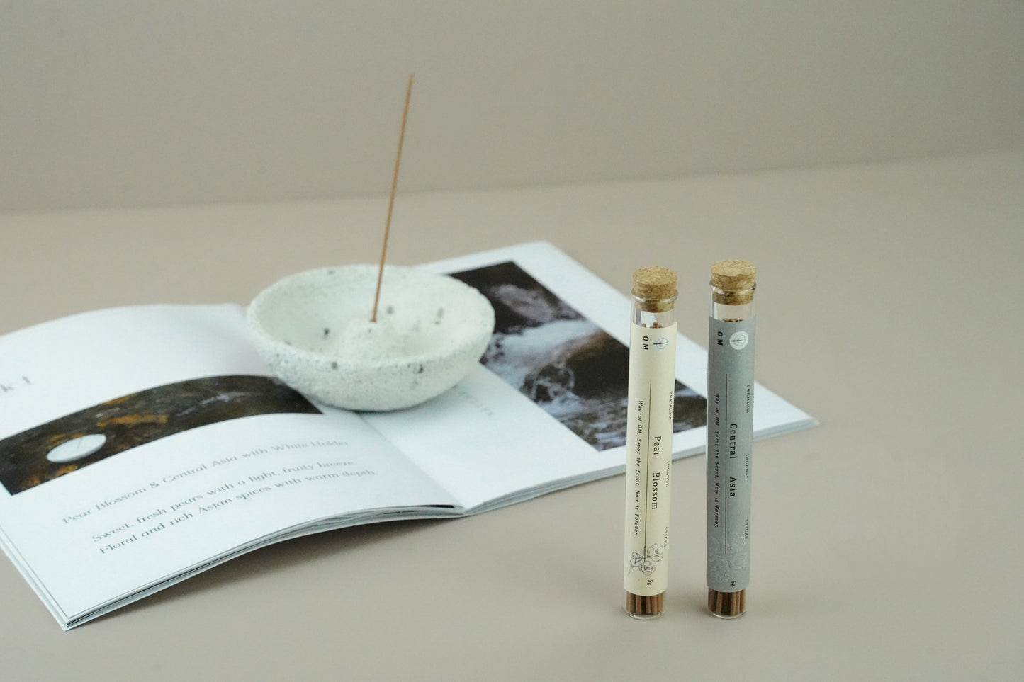 White volcanic incense holder with burning sticks on white table – OM ritual fragrance set with Pear Blossom and Central Asia