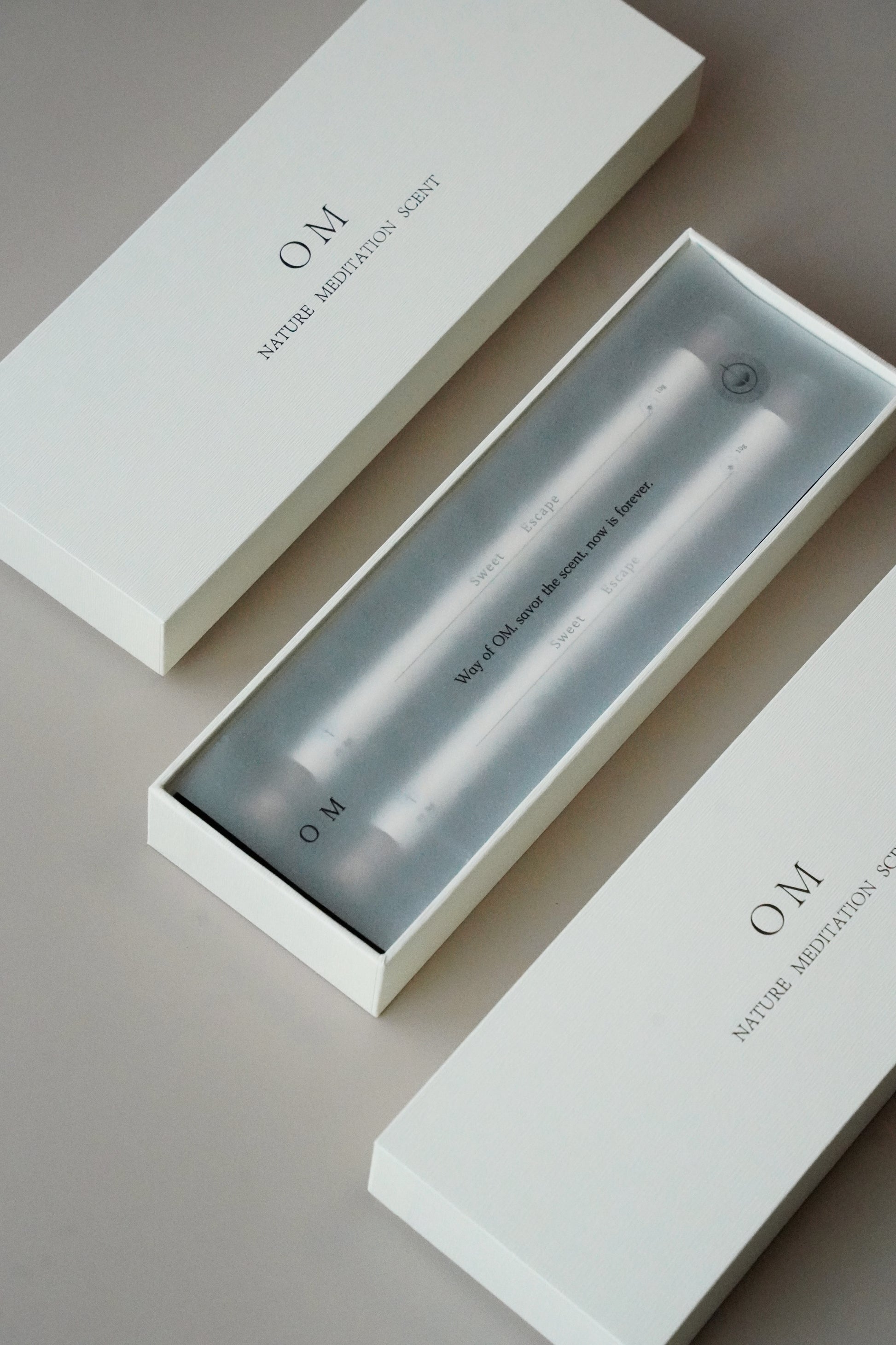 Close-up of incense packaging tube with OM branding – elegant floral and ambergris incense